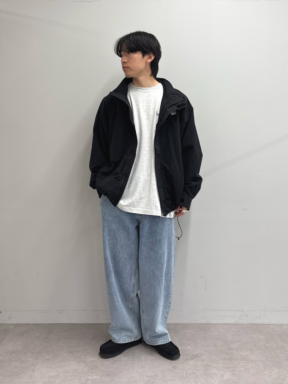 ブラック系のナイロンジャケット、グレー系のTシャツ/カットソー、ブルー系のデニムパンツを着用したメンズの春コーディネートの2枚目の写真