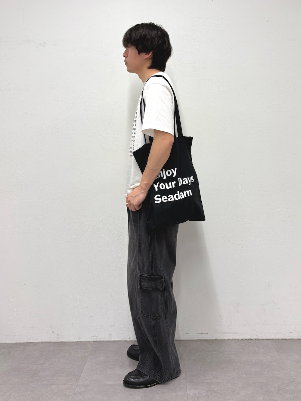 ホワイト系のTシャツ/カットソー、ブラック系のトートバッグ、ブラック系のカーゴパンツを着用したメンズの春コーディネートの2枚目の写真