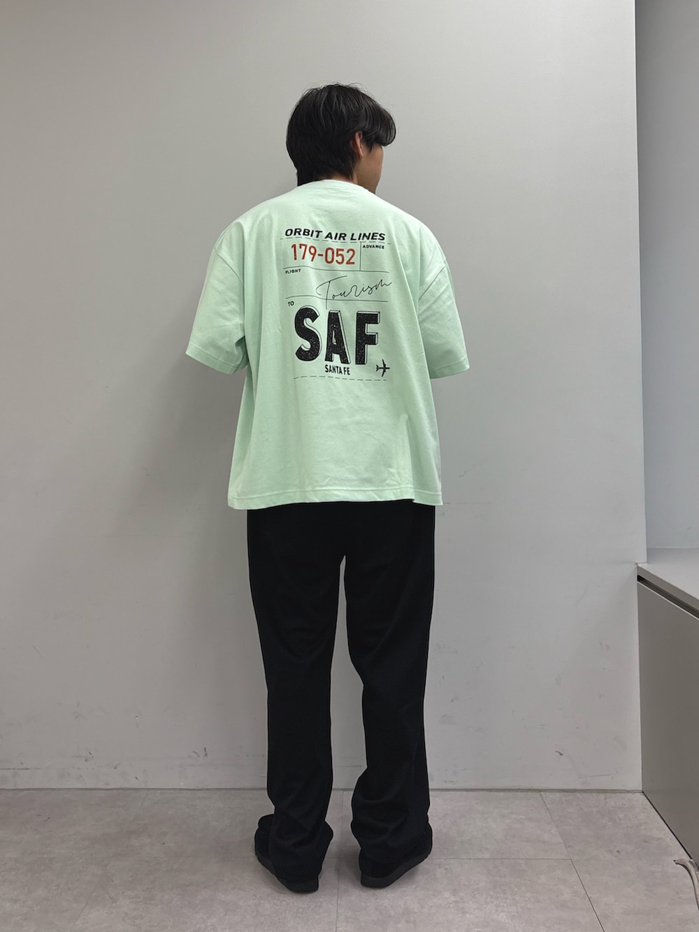ブルー系のブルゾン、グリーン系のTシャツ/カットソー、ブラック系のスラックスを着用したメンズの春コーディネートの3枚目の写真