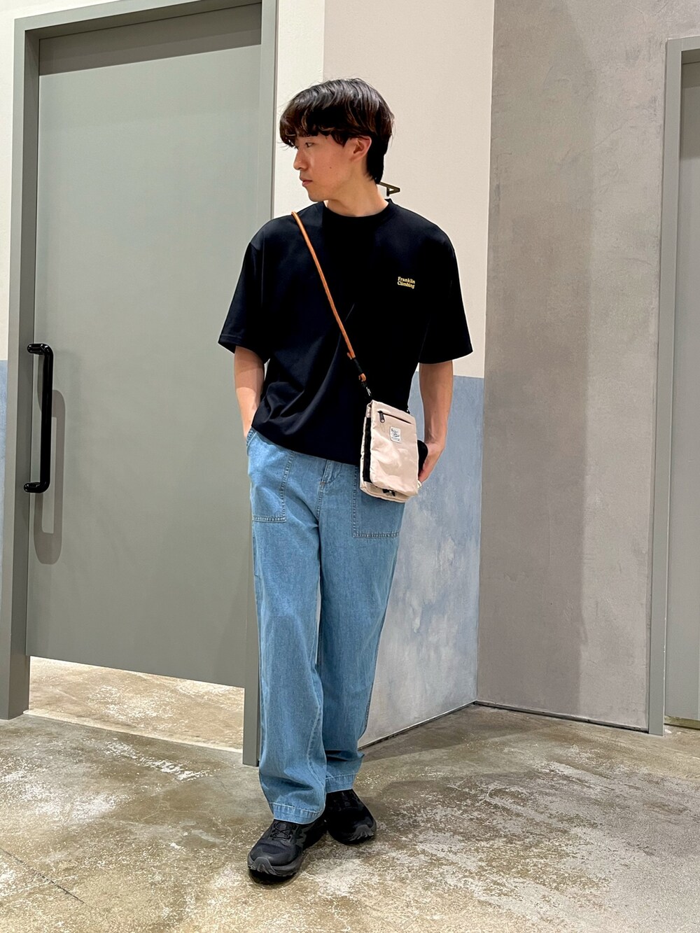 ブルー系のデニムパンツ、ベージュ系のショルダーバッグ、ブラック系のTシャツ/カットソーを着用したメンズの夏コーディネートの3枚目の写真