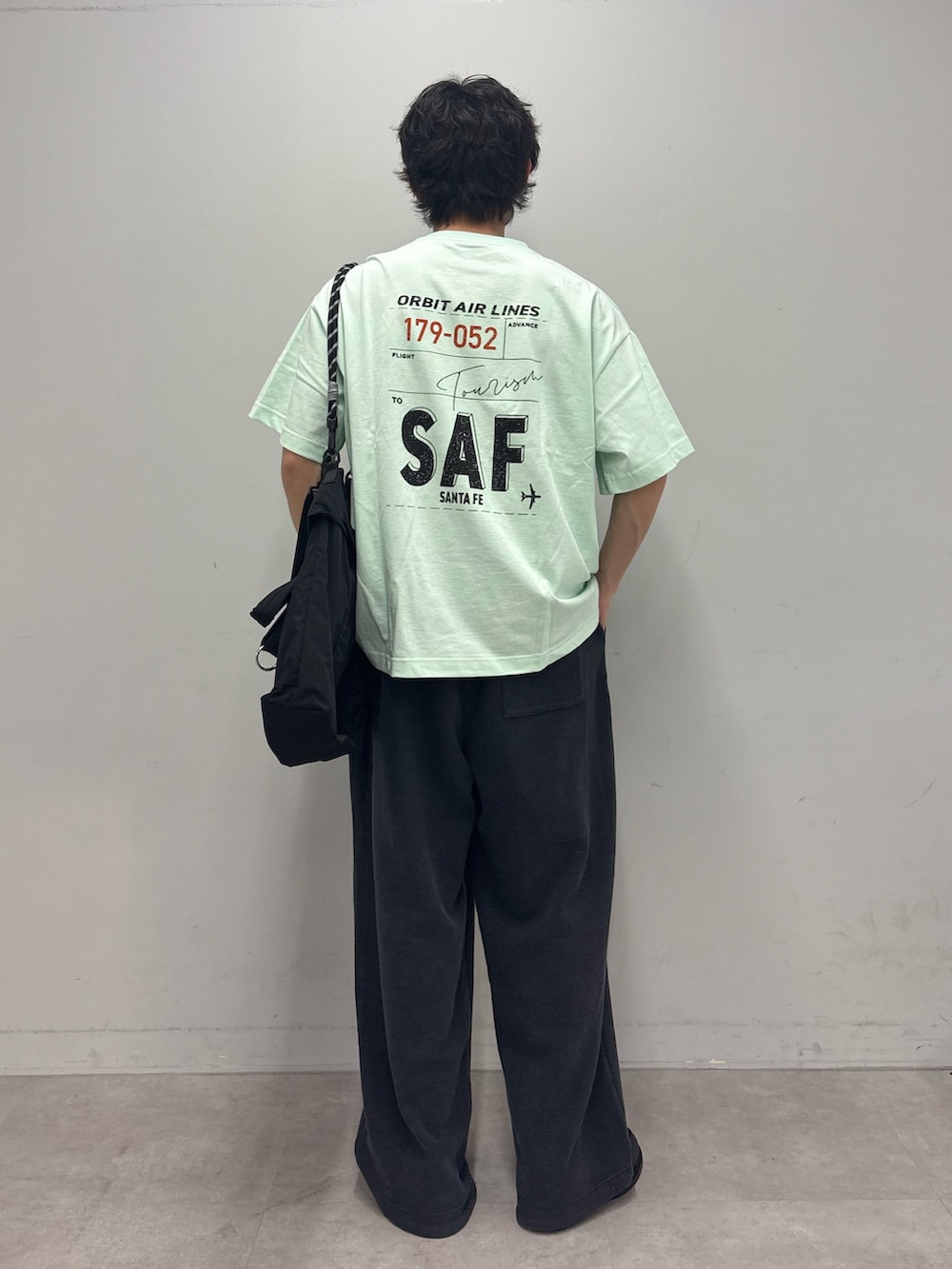 グリーン系のTシャツ/カットソー、ブラック系のショルダーバッグ、ブラック系のスウェットパンツを着用したメンズの春コーディネートの3枚目の写真