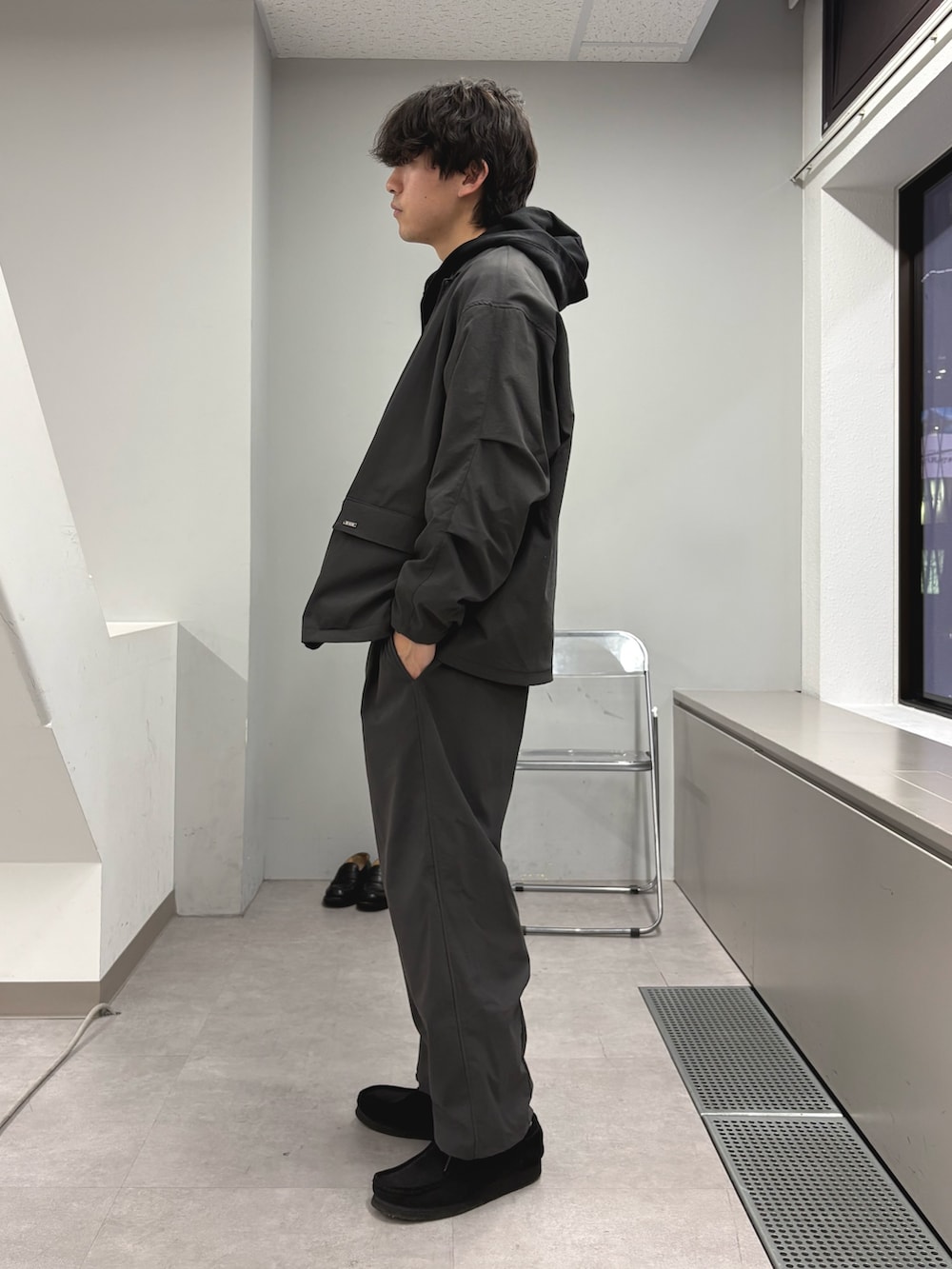 グレー系のテーラードジャケット、ブラック系のパーカー、グレー系のスラックスを着用したメンズの冬コーディネートの2枚目の写真