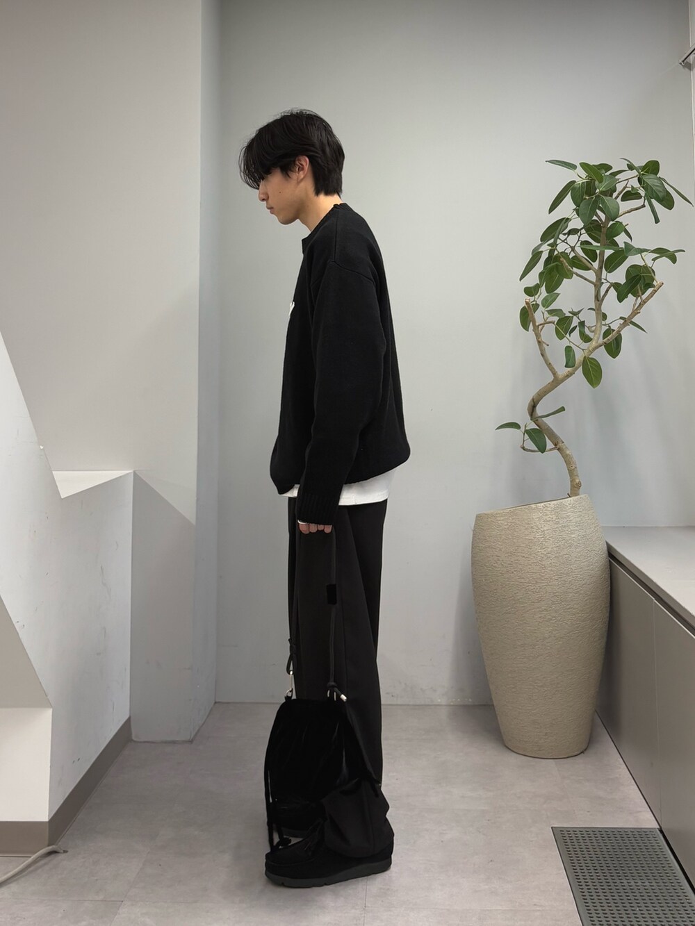 ブラック系のニット/セーター、ブラック系のスラックス、ブラック系のショルダーバッグを着用したメンズの春コーディネートの2枚目の写真