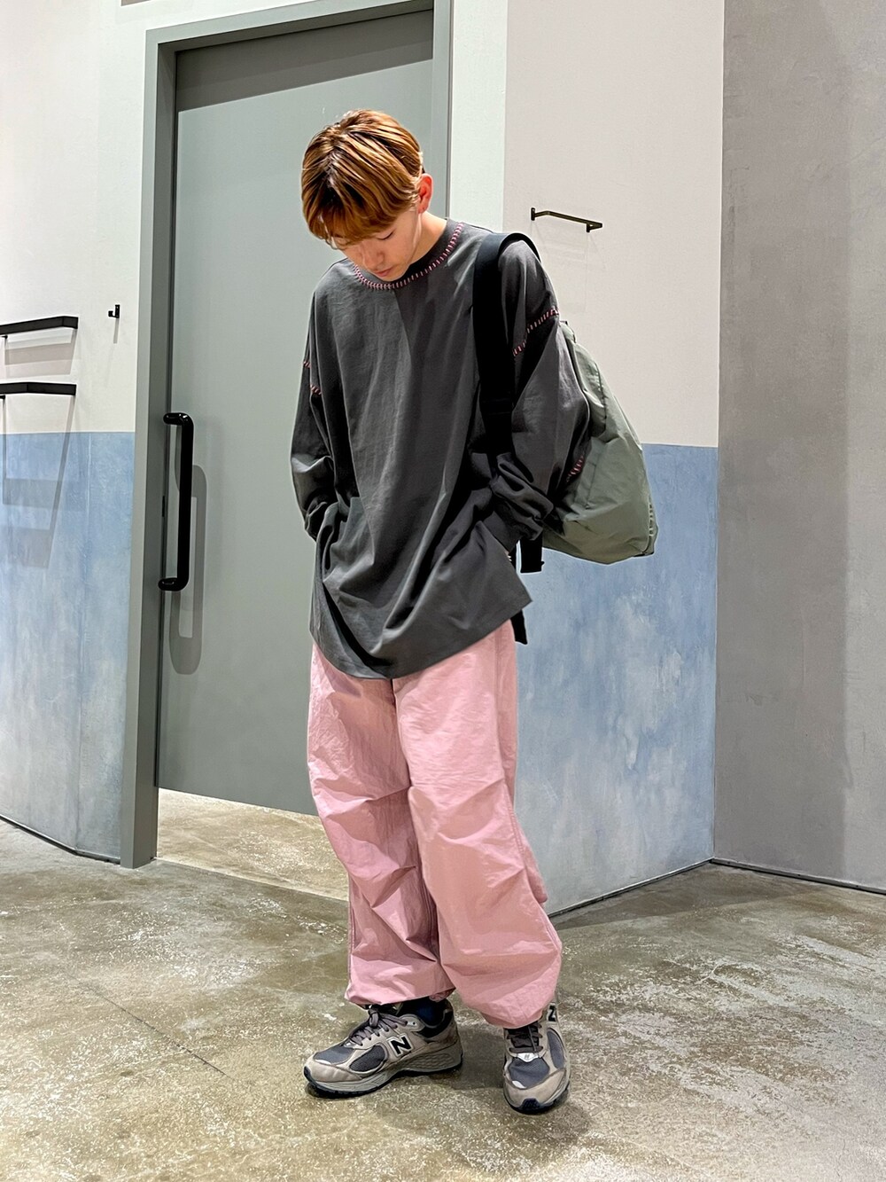 グリーン系のショルダーバッグ、グレー系のTシャツ/カットソー、ピンク系のカーゴパンツを着用したメンズの秋コーディネートの3枚目の写真