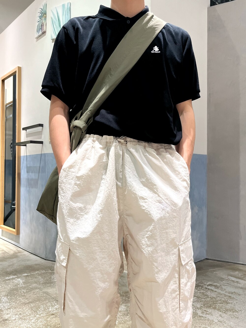 ブラック系のスニーカー、ホワイト系のカーゴパンツ、ブラック系のポロシャツを着用したメンズの春コーディネートの3枚目の写真