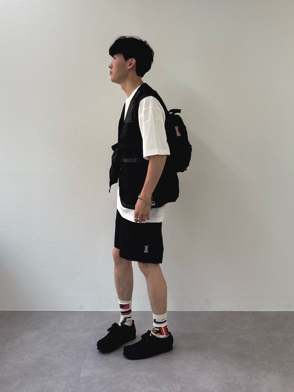 ブラック系のベスト、ブラック系のその他パンツ、ブラック系のバックパック/リュックを着用したメンズの春コーディネートの2枚目の写真