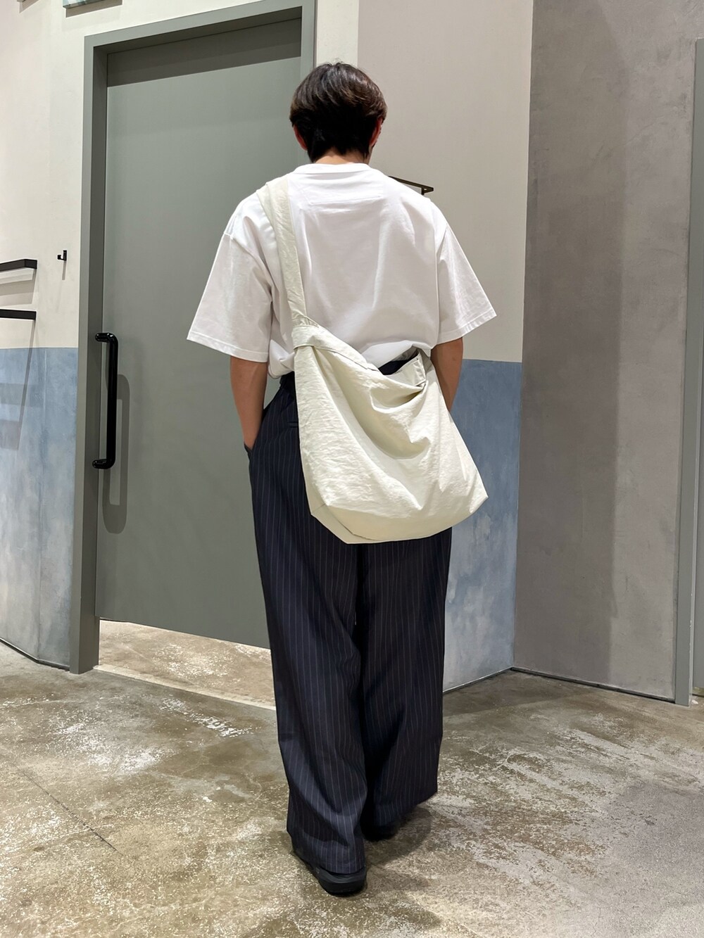 ブラック系のスニーカー、グレー系のスラックス、ホワイト系のTシャツ/カットソーを着用したメンズの春コーディネートの2枚目の写真