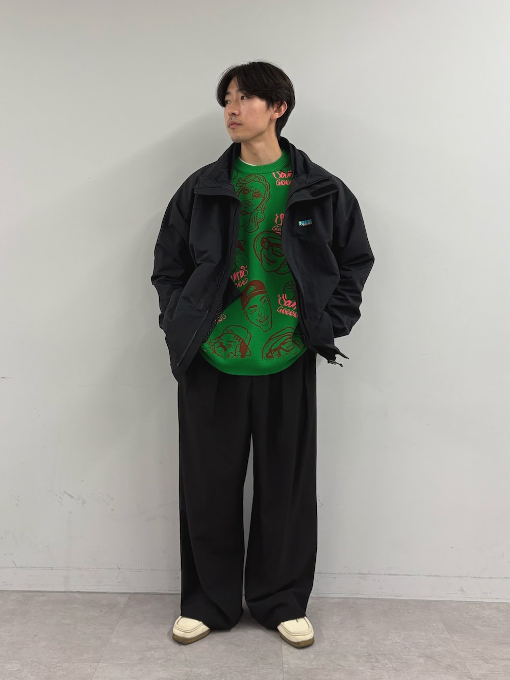 ブラック系のナイロンジャケット、グリーン系のニット/セーター、ブラック系のスラックスを着用したメンズの秋コーディネートの3枚目の写真