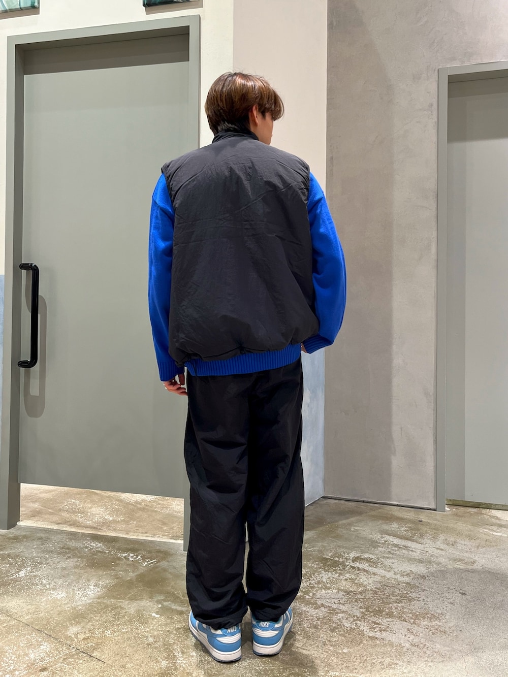 ブルー系のスニーカー、ブラック系のベスト、ブラック系のその他パンツを着用したメンズの冬コーディネートの3枚目の写真