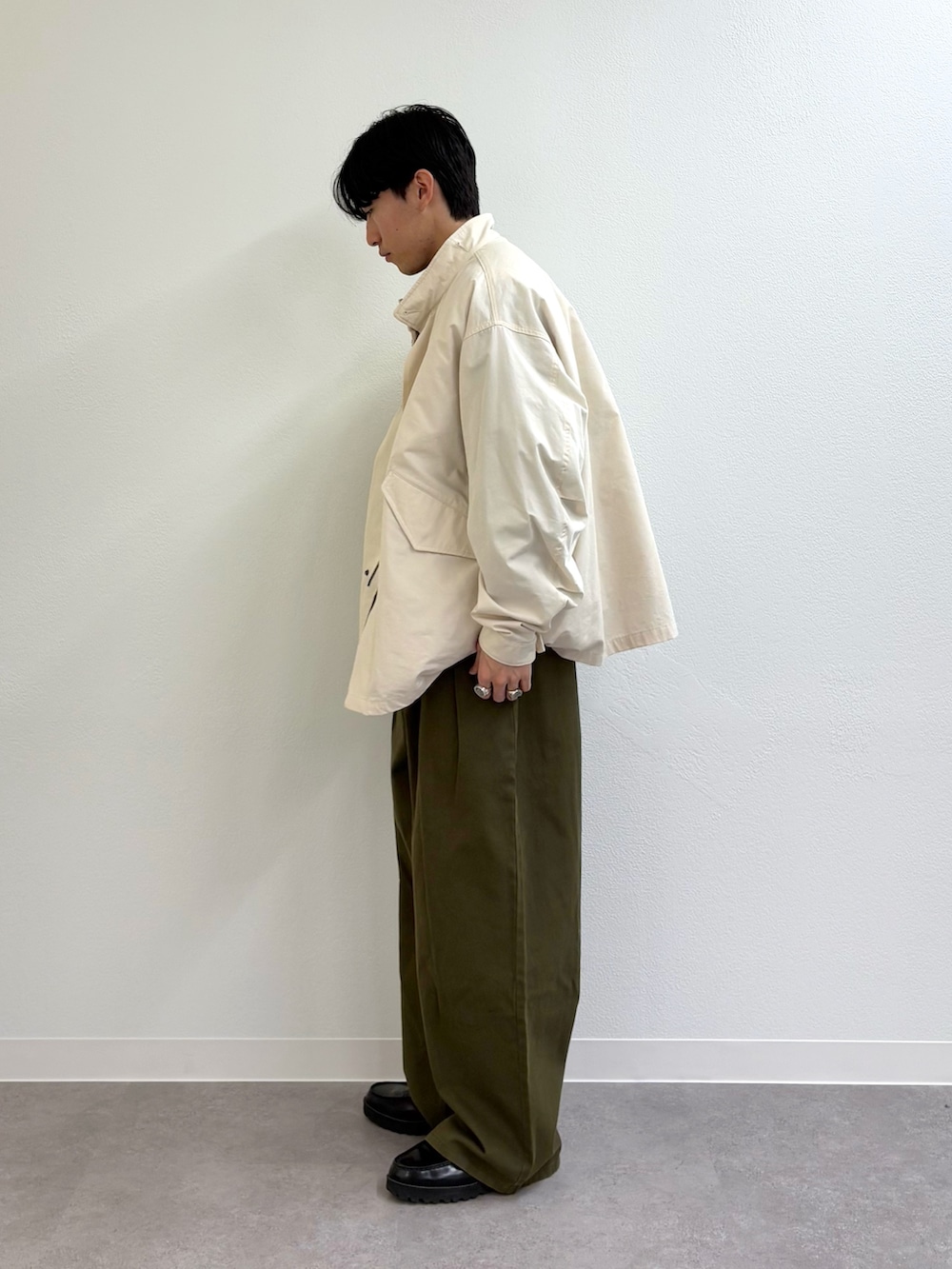 ホワイト系のモッズコート、グリーン系のスラックス、ブラック系のローファーを着用したメンズの冬コーディネートの2枚目の写真