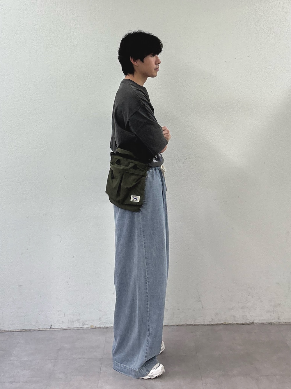 ブラック系のTシャツ/カットソー、グリーン系のショルダーバッグ、ブルー系のデニムパンツを着用したメンズの春コーディネートの2枚目の写真