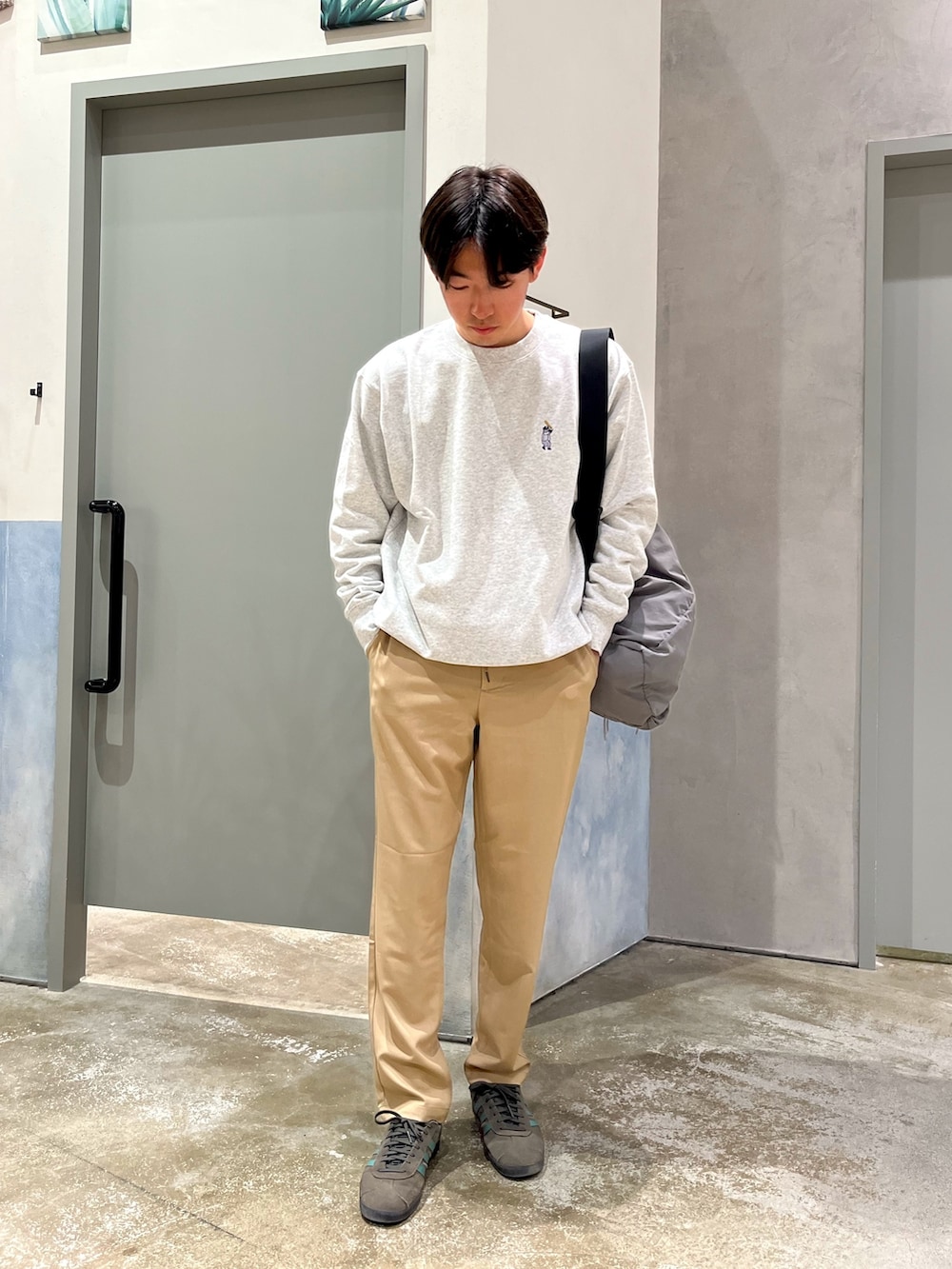 グレー系のスウェット、ブラック系のMA-1、ベージュ系のデニムパンツを着用したメンズの春コーディネートの3枚目の写真