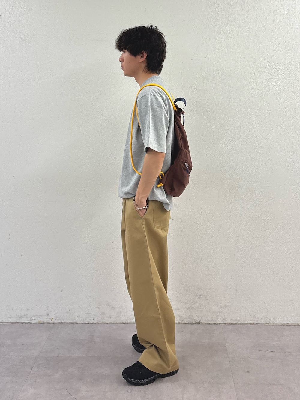 グレー系のTシャツ/カットソー、ブラウン系のバックパック/リュック、ベージュ系のデニムパンツを着用したメンズの春コーディネートの2枚目の写真