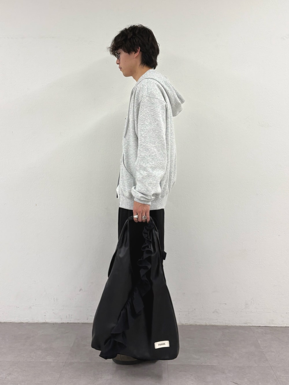 グレー系のパーカー、ホワイト系のTシャツ/カットソー、ブラック系のスラックスを着用したメンズの秋コーディネートの2枚目の写真