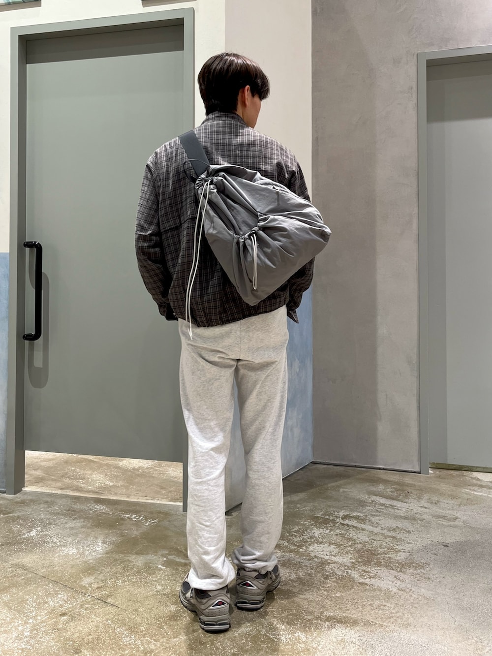 グレー系のスニーカー、グレー系のスウェットパンツ、ブラック系のニット/セーターを着用したメンズの冬コーディネートの2枚目の写真