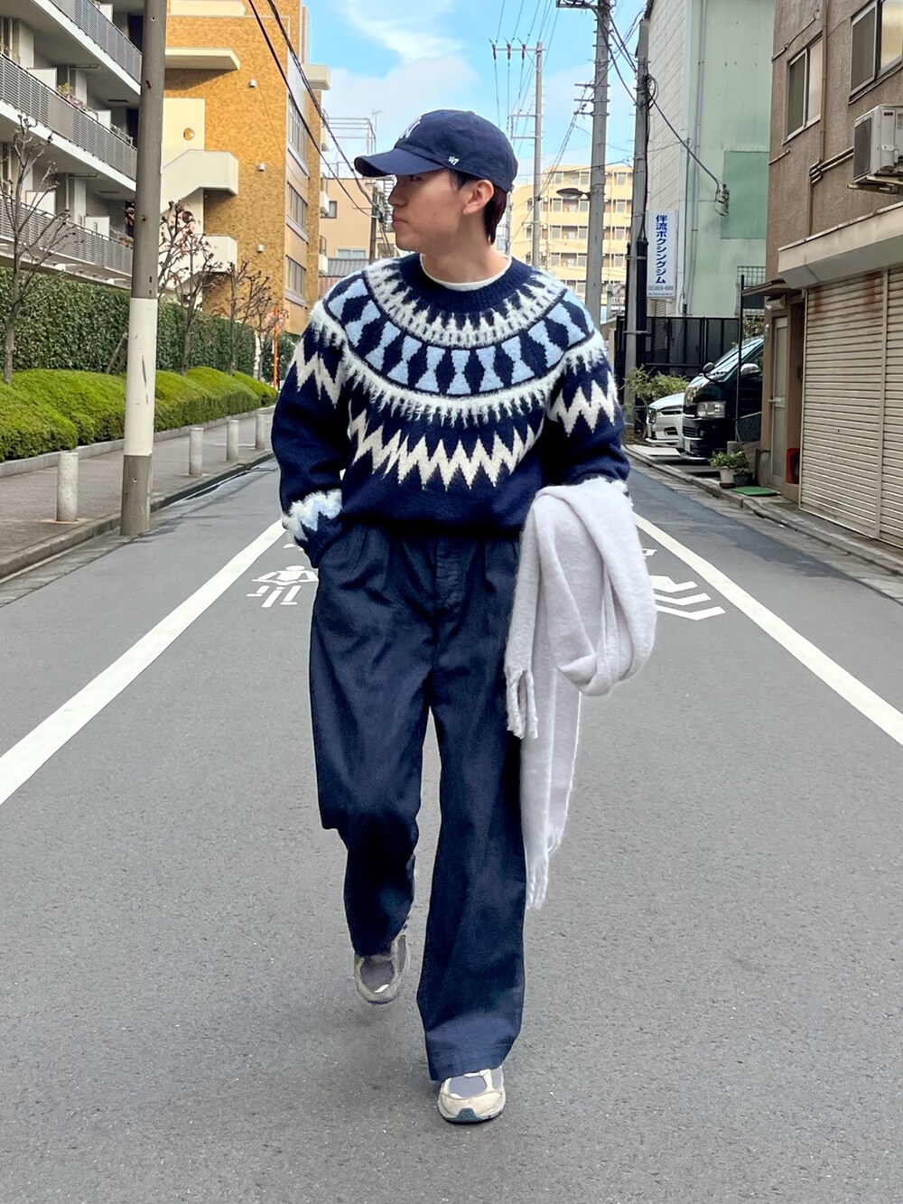 グレー系のスニーカー、ブラック系のデニムパンツ、ブルー系のニット/セーターを着用したメンズの冬コーディネートの2枚目の写真