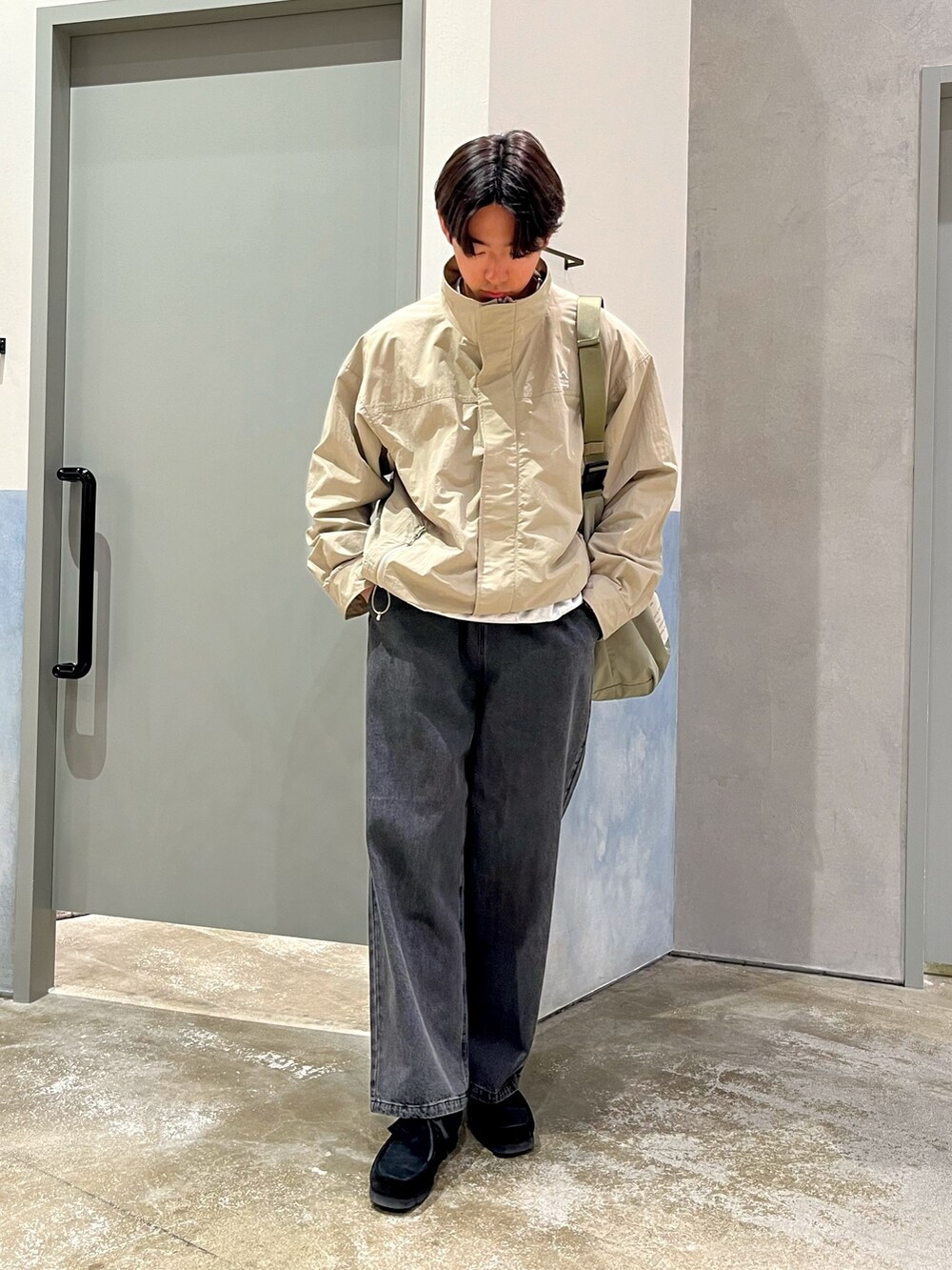 ブラック系のスニーカー、ブラック系のデニムパンツ、グレー系のナイロンジャケットを着用したメンズの春コーディネートの2枚目の写真