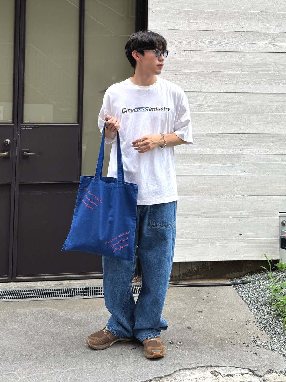 ホワイト系のTシャツ/カットソー、ブルー系のトートバッグ、ブルー系のデニムパンツを着用したメンズの夏コーディネートの2枚目の写真