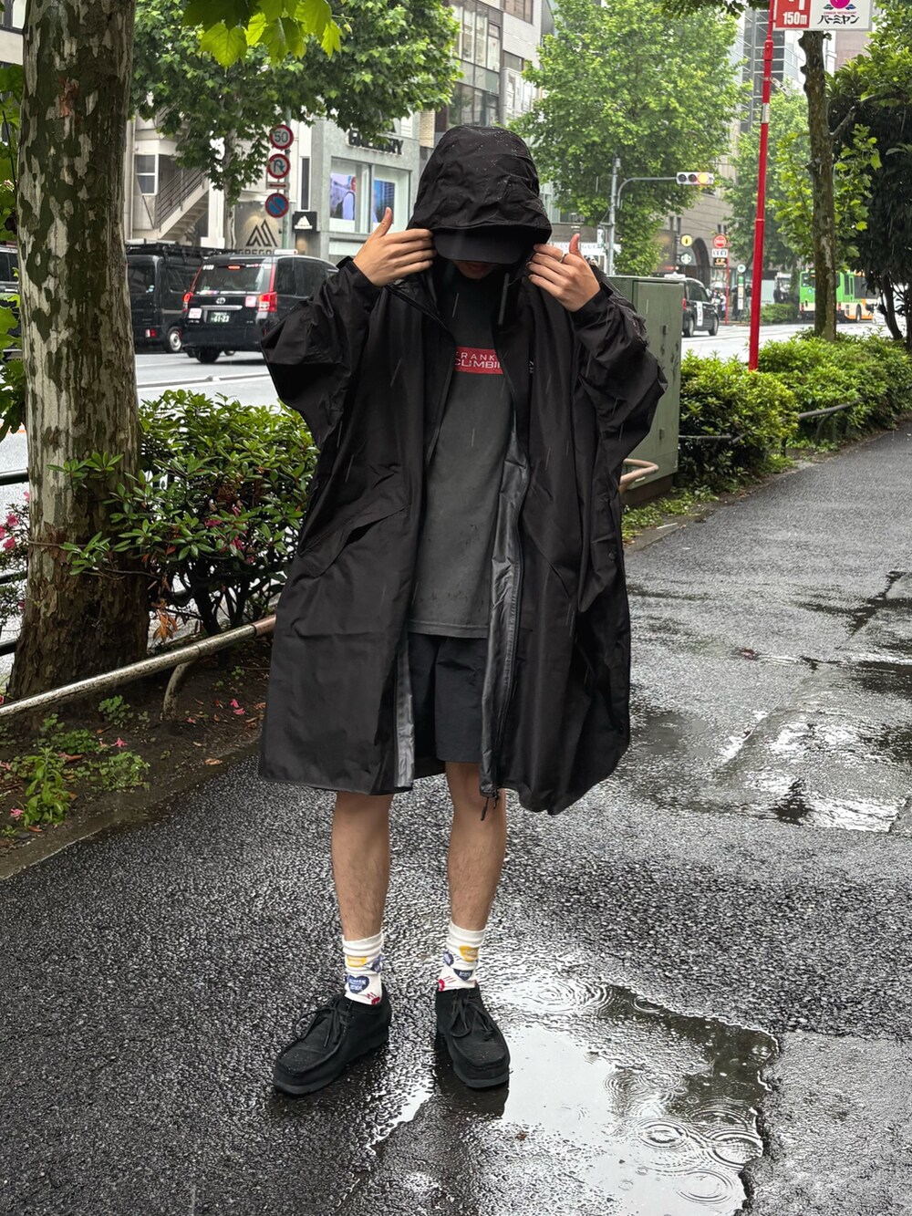 ブラック系のキャップ、ブラック系のレインコート/ポンチョを着用したメンズの夏コーディネートの2枚目の写真