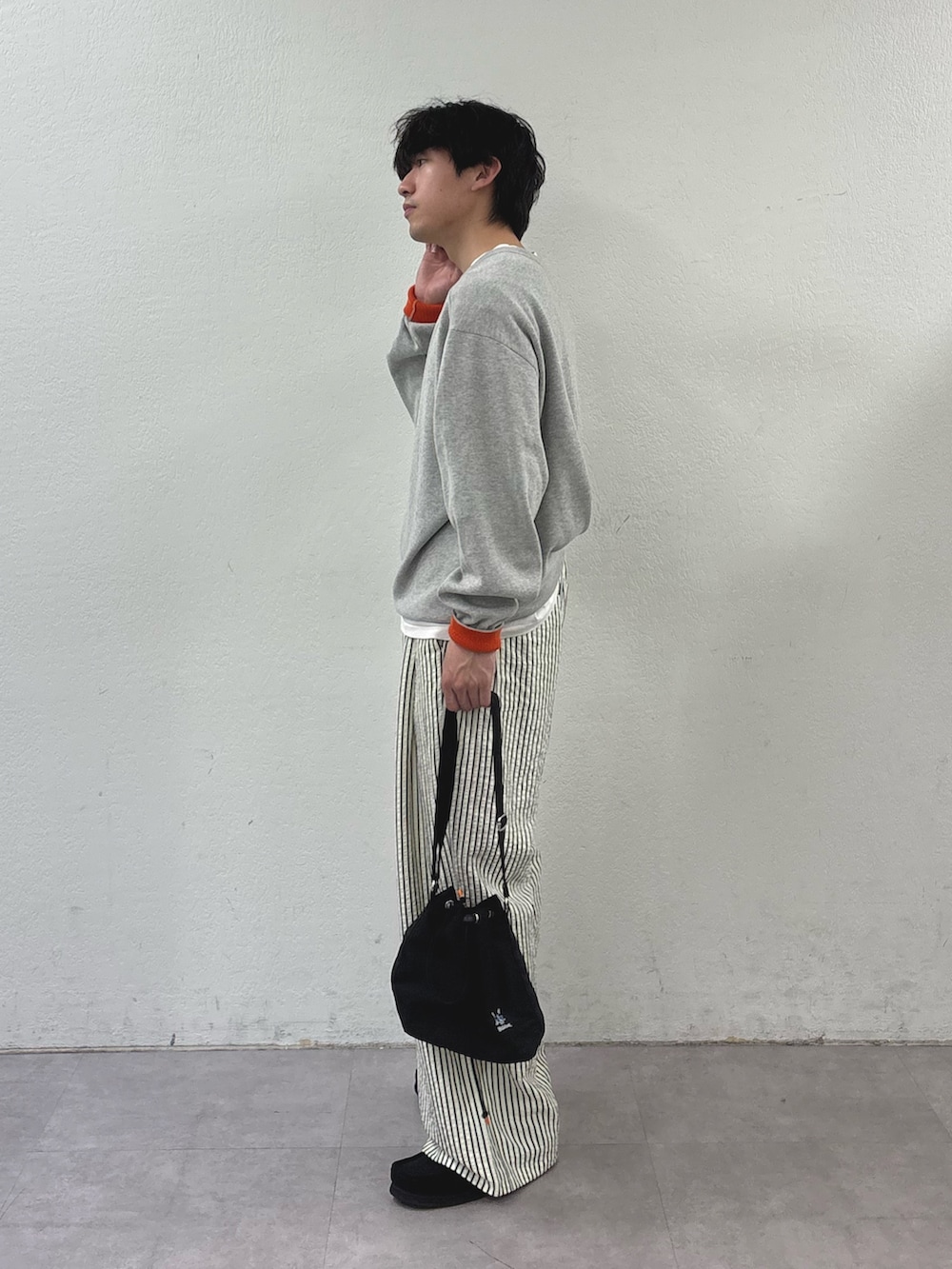 グレー系のニット/セーター、ホワイト系のその他パンツ、ブラック系のショルダーバッグを着用したメンズの春コーディネートの2枚目の写真