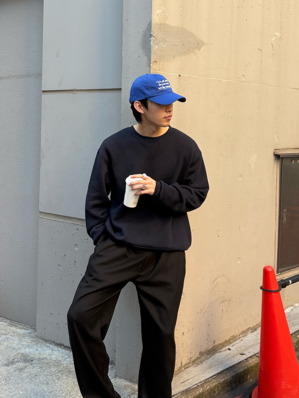 ブラック系のスラックス、ブルー系のスウェット、ブルー系のキャップを着用したメンズの冬コーディネートの2枚目の写真