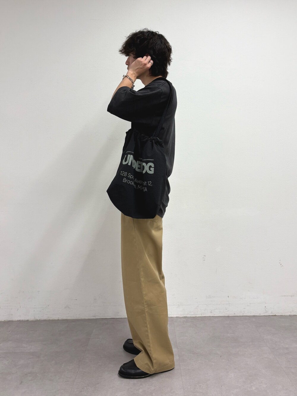 ブラック系のTシャツ/カットソー、ブラック系のトートバッグ、ベージュ系のデニムパンツを着用したメンズの夏コーディネートの2枚目の写真