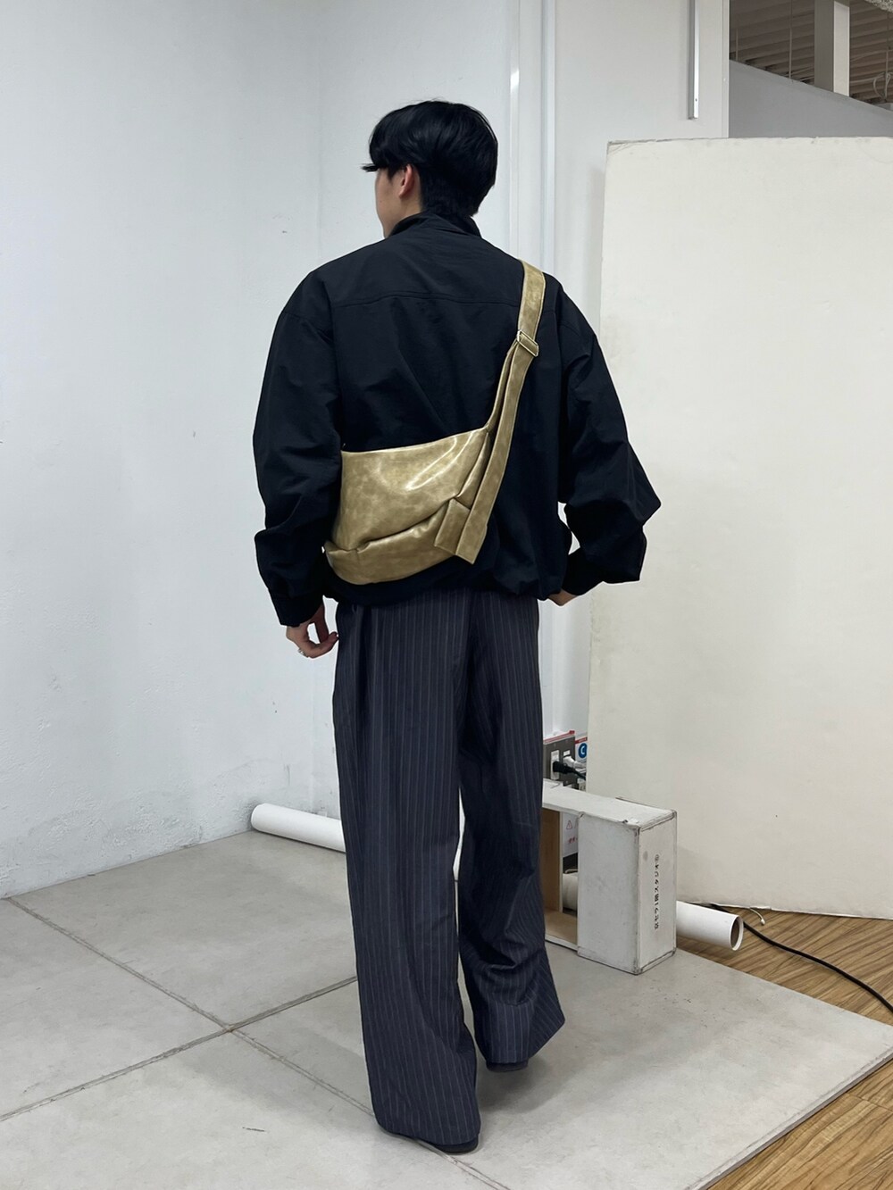 グレー系のスラックス、グレー系のスニーカー、ブラック系のナイロンジャケットを着用したメンズの秋コーディネートの3枚目の写真