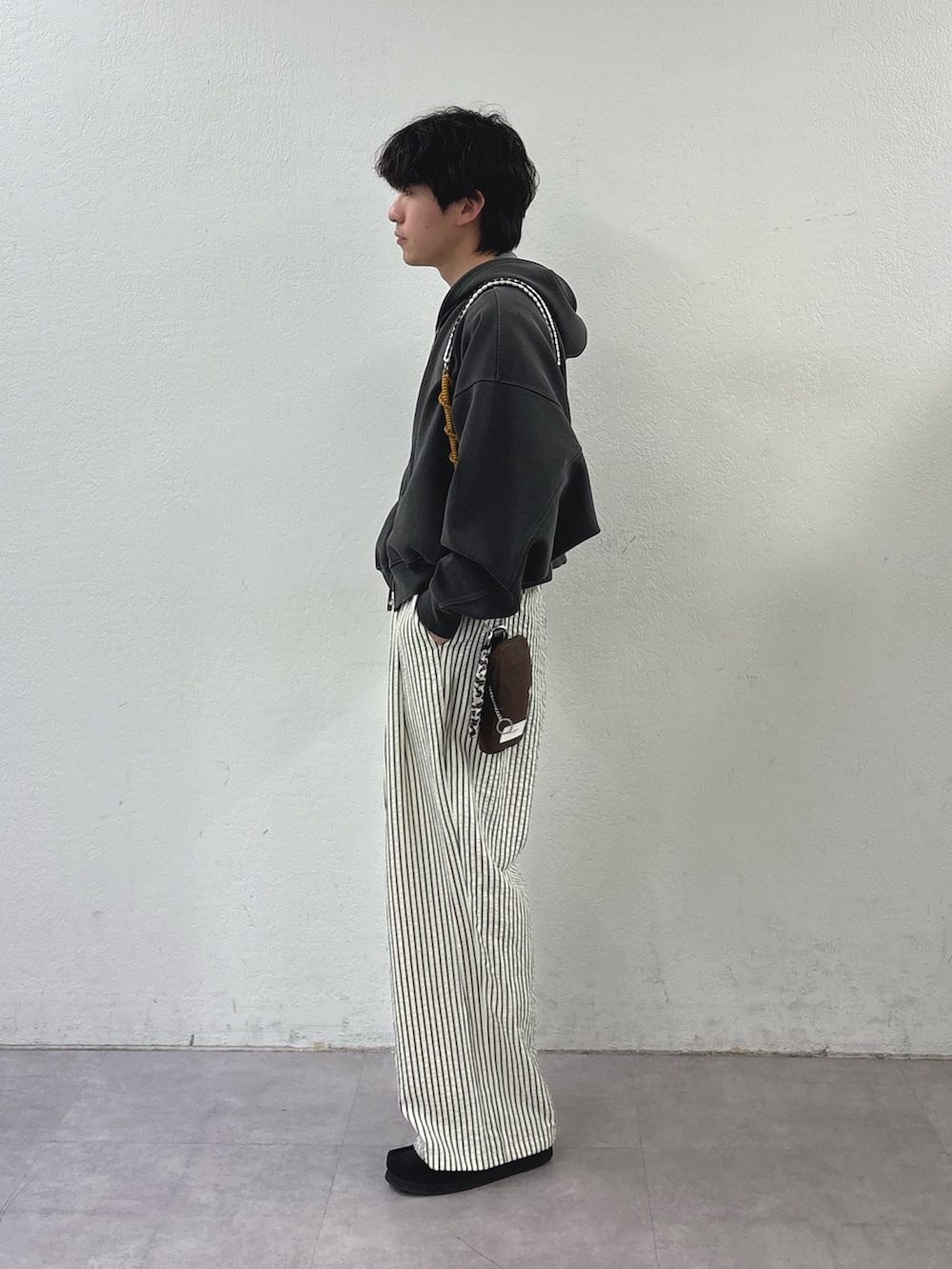 グレー系のパーカー、ブラウン系のショルダーバッグ、ホワイト系のその他パンツを着用したメンズの春コーディネートの2枚目の写真