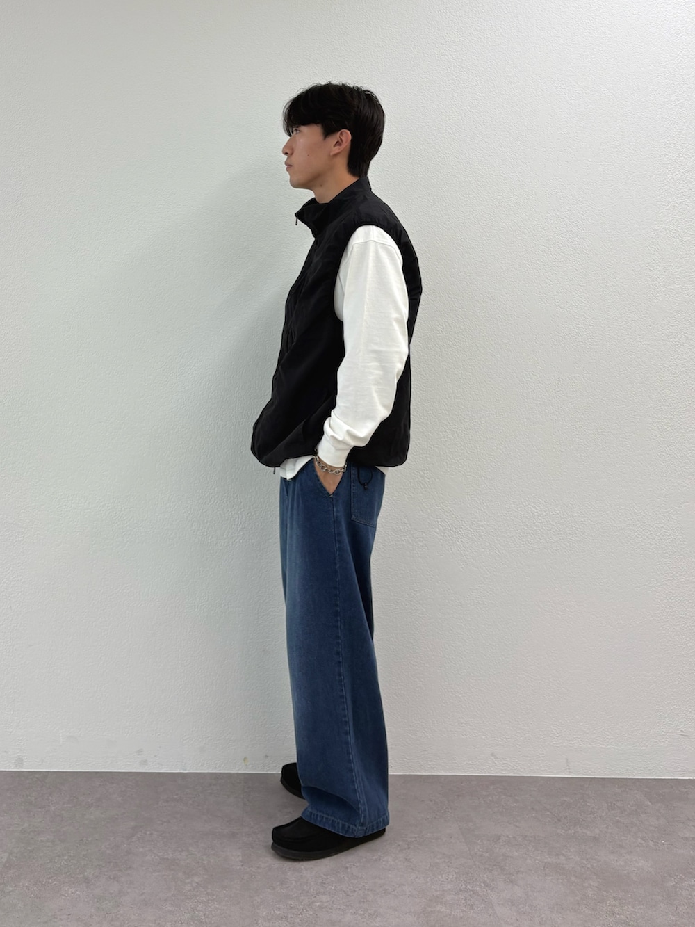 ブラック系のベスト、ホワイト系のTシャツ/カットソー、ブルー系のデニムパンツを着用したメンズの秋コーディネートの2枚目の写真