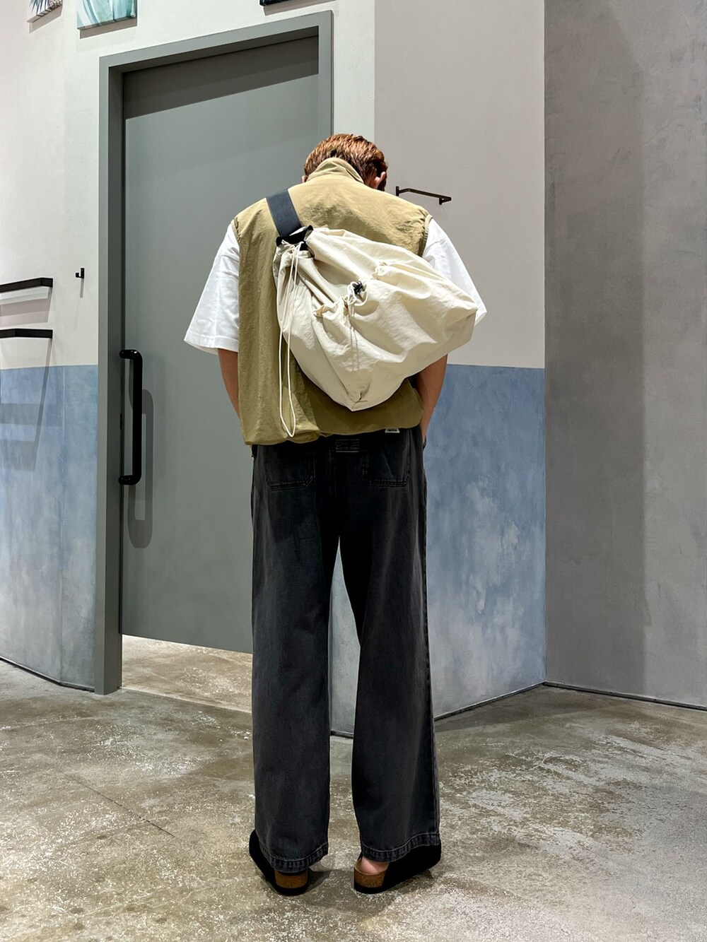 ホワイト系のショルダーバッグ、ホワイト系のTシャツ/カットソー、ベージュ系のベストを着用したメンズの秋コーディネートの3枚目の写真