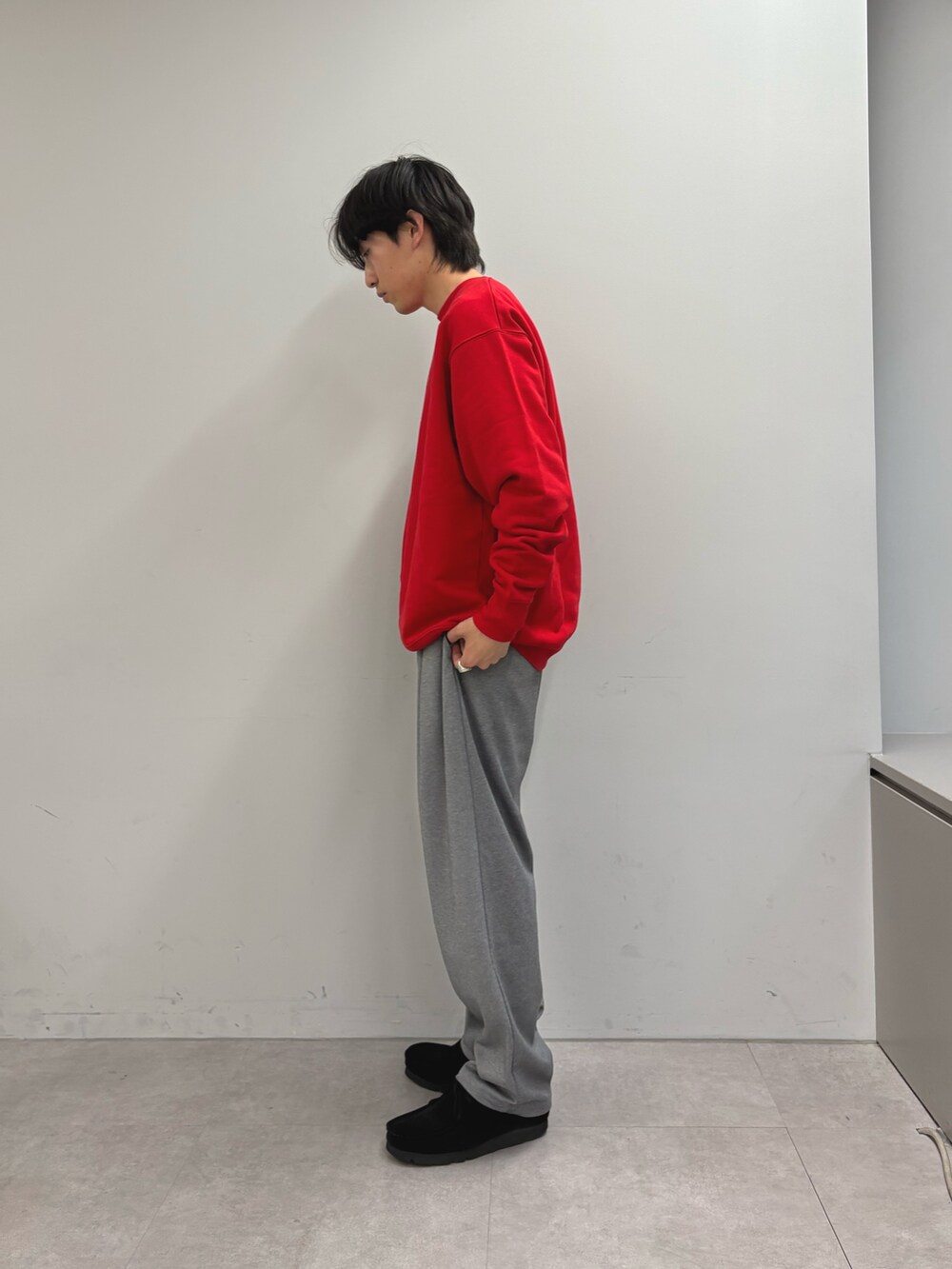 レッド系のスウェット、グレー系のスラックスを着用したメンズの春コーディネートの2枚目の写真