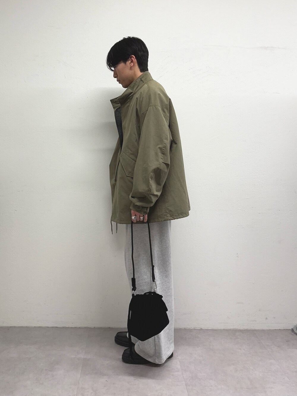 グレー系のスウェットパンツ、ブラック系のショルダーバッグ、グリーン系のモッズコートを着用したメンズの冬コーディネートの2枚目の写真