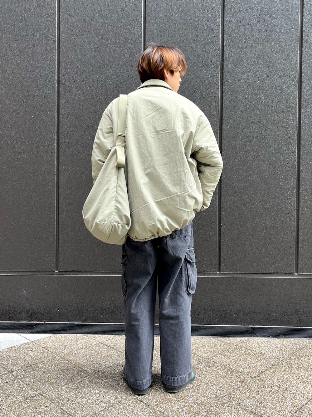 グレー系のスニーカー、ブラック系のカーゴパンツ、レッド系のスウェットを着用したメンズの冬コーディネートの2枚目の写真