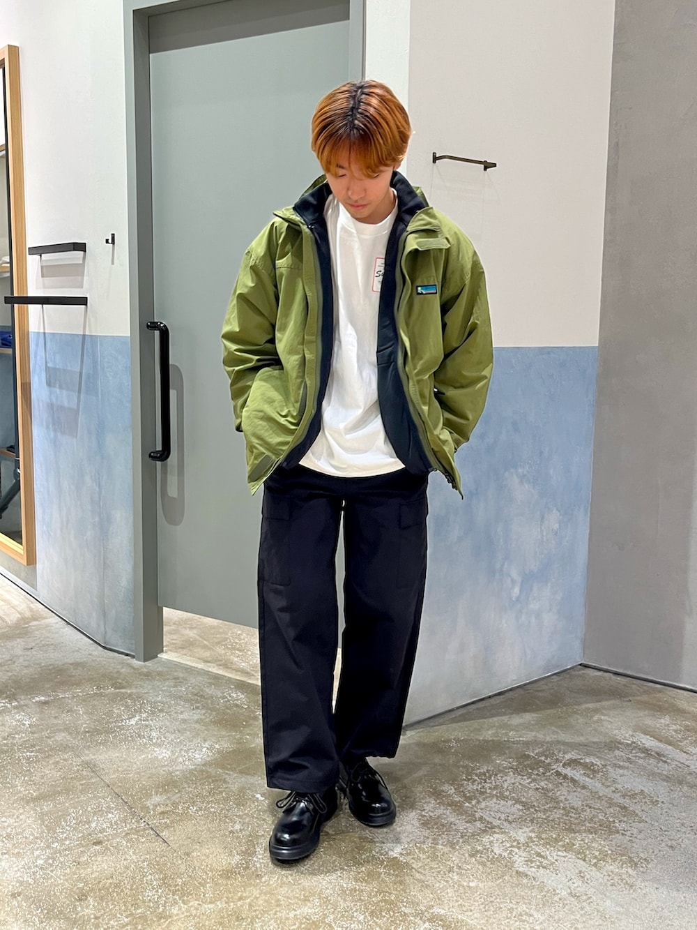 ブラック系のその他シューズ、ブラック系のカーゴパンツ、グリーン系のナイロンジャケットを着用したメンズの秋コーディネートの2枚目の写真