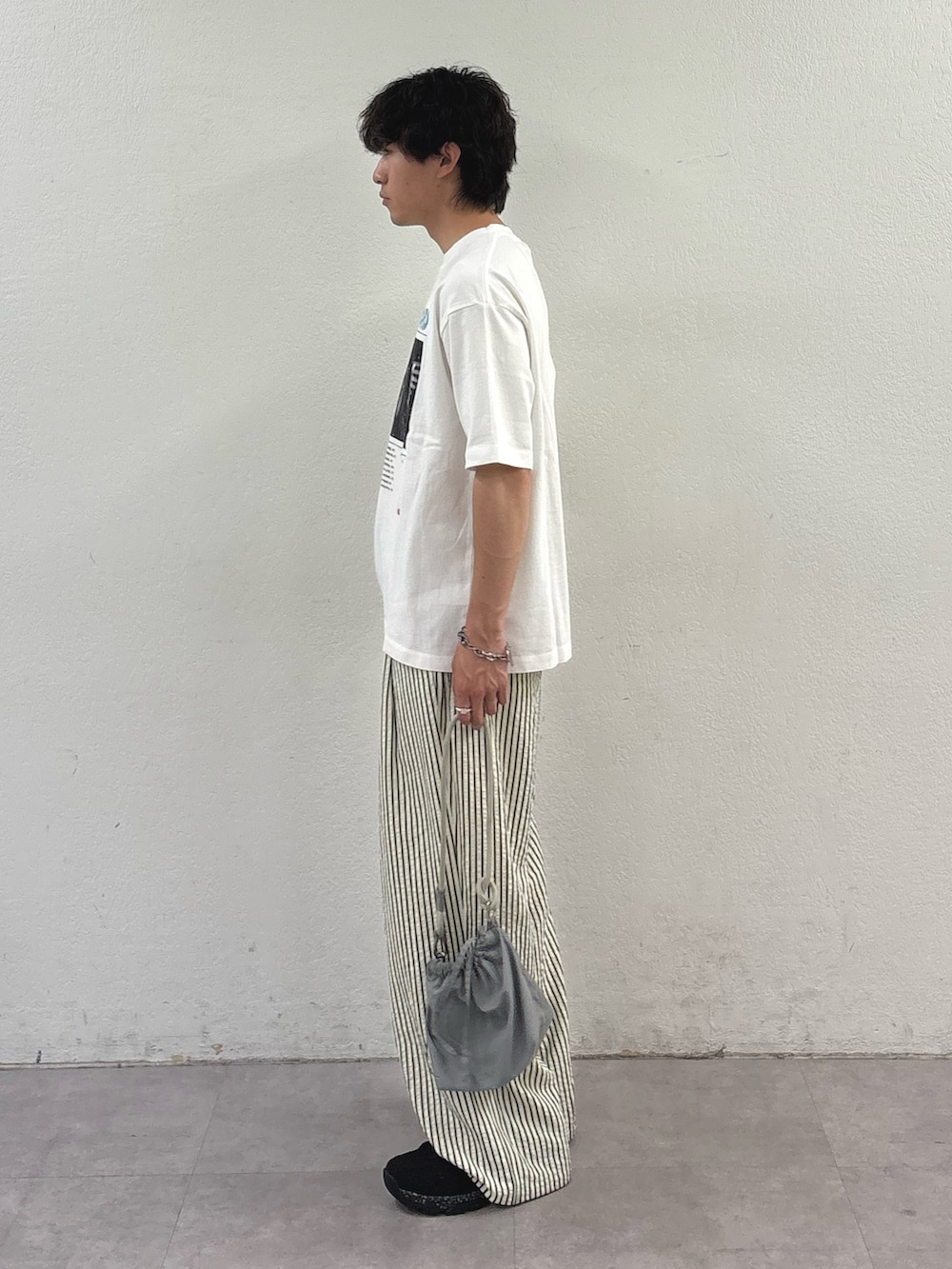 ホワイト系のその他パンツ、グレー系のショルダーバッグ、ホワイト系のTシャツ/カットソーを着用したメンズの春コーディネートの2枚目の写真