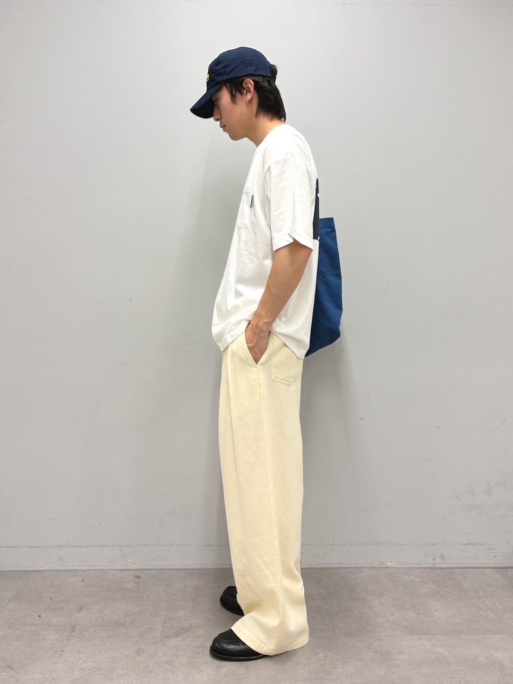 ブルー系のトートバッグ、ホワイト系のTシャツ/カットソー、ホワイト系のスラックスを着用したメンズの春コーディネートの2枚目の写真