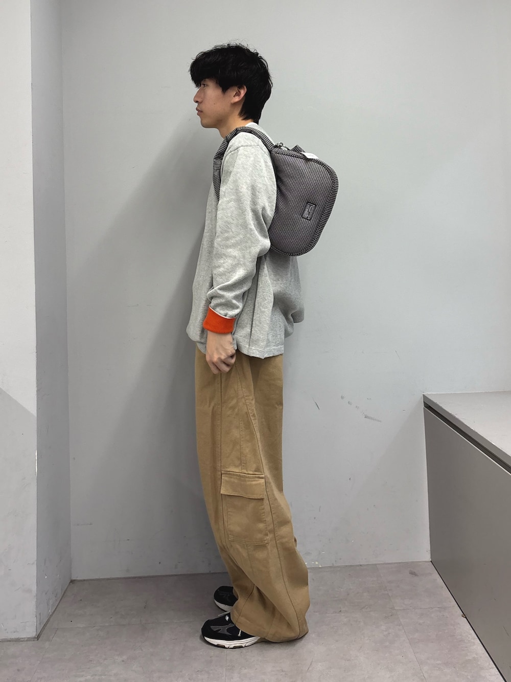 グレー系のニット/セーター、ベージュ系のカーゴパンツ、ブラック系のショルダーバッグを着用したメンズの春コーディネートの2枚目の写真