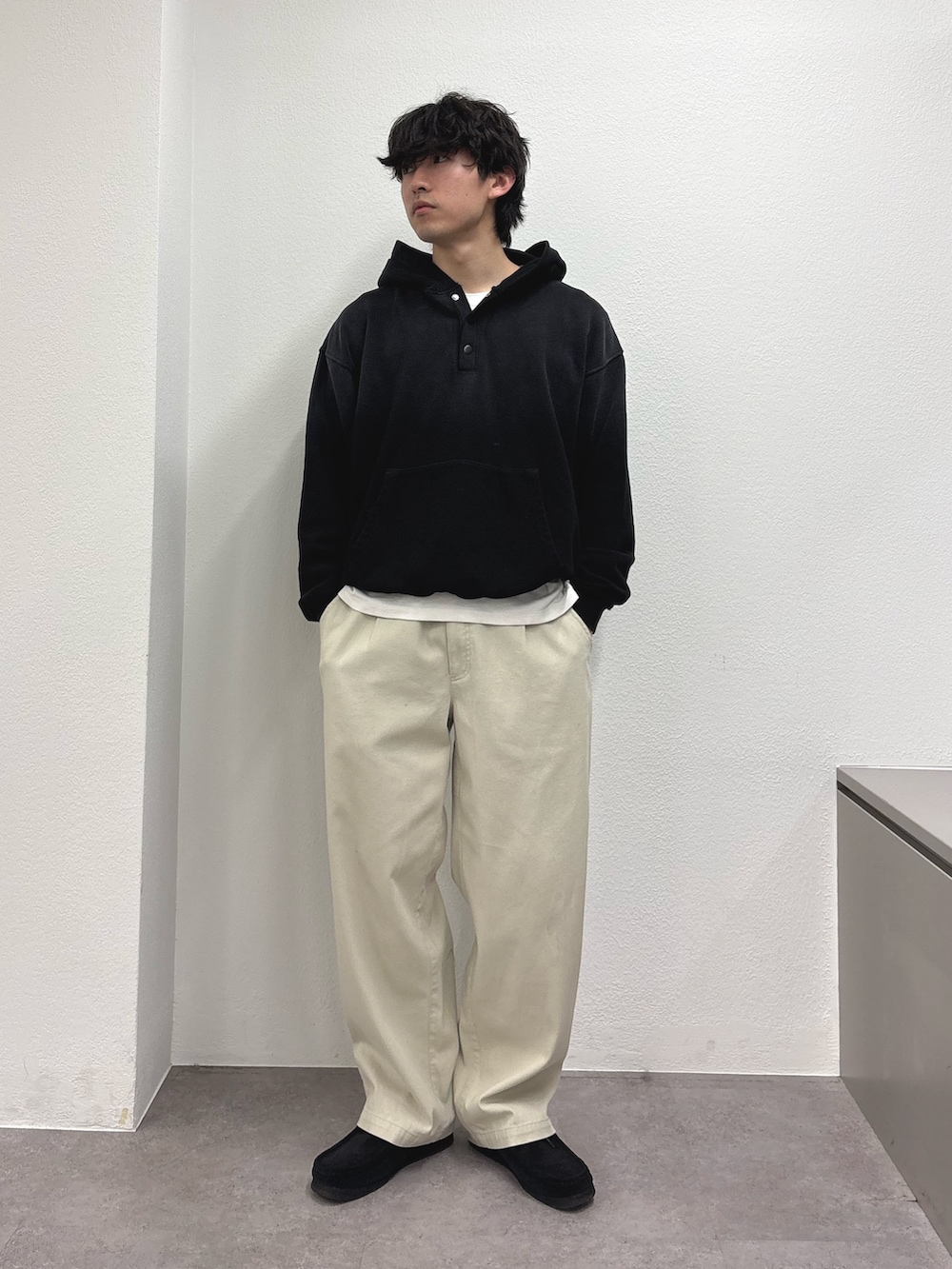 ブラック系のパーカー、ホワイト系のチノパンツ、グリーン系のモッズコートを着用したメンズの冬コーディネートの3枚目の写真