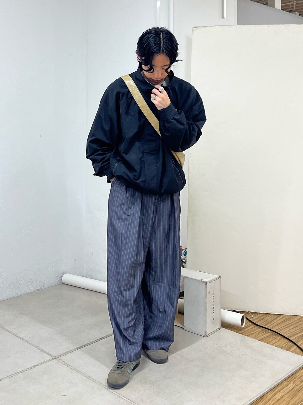 グレー系のスラックス、グレー系のスニーカー、ブラック系のナイロンジャケットを着用したメンズの秋コーディネートの2枚目の写真