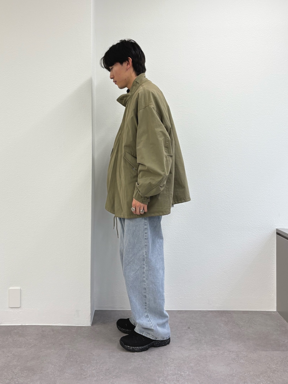 ブルー系のデニムパンツ、ブラック系のスニーカー、グリーン系のモッズコートを着用したメンズの春コーディネートの2枚目の写真