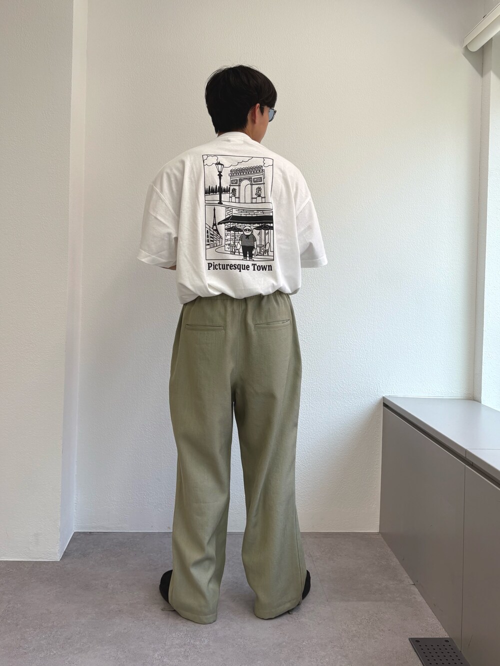 ホワイト系のTシャツ/カットソー、グリーン系のスラックスを着用したメンズの夏コーディネートの2枚目の写真