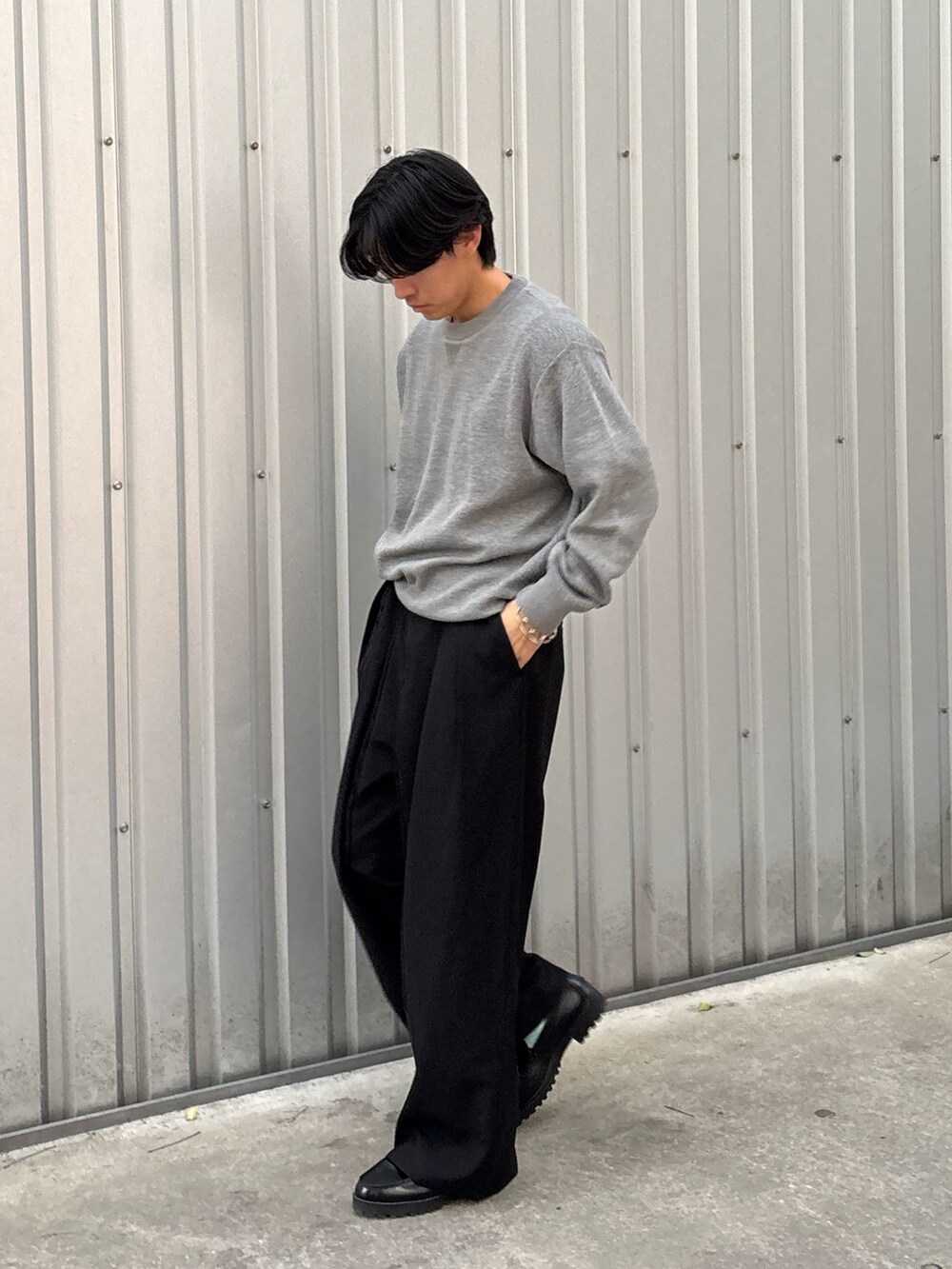 グレー系のニット/セーター、ブラック系のスラックスを着用したメンズの秋コーディネートの2枚目の写真