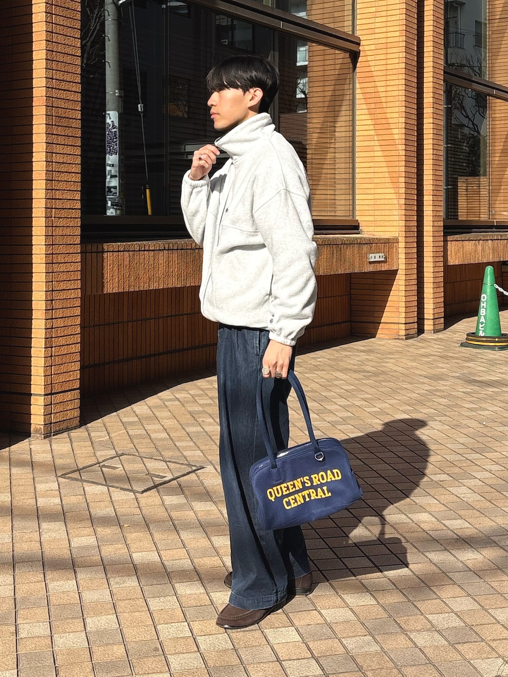 グレー系のブルゾン、ブルー系のデニムパンツ、ブルー系のボストンバッグを着用したメンズの冬コーディネートの2枚目の写真