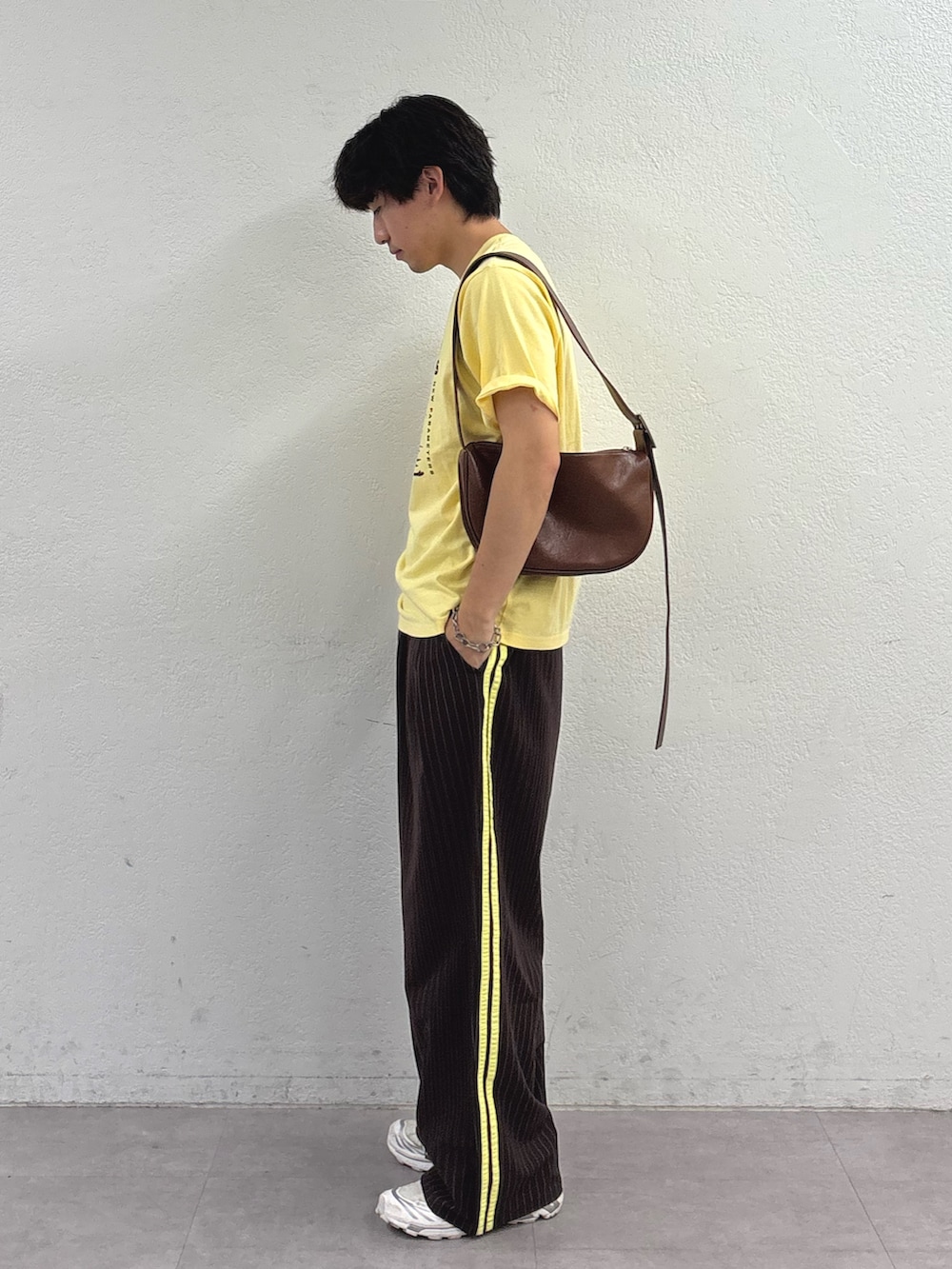 イエロー系のTシャツ/カットソー、ブラウン系のショルダーバッグ、ブラウン系のスラックスを着用したメンズの夏コーディネートの2枚目の写真