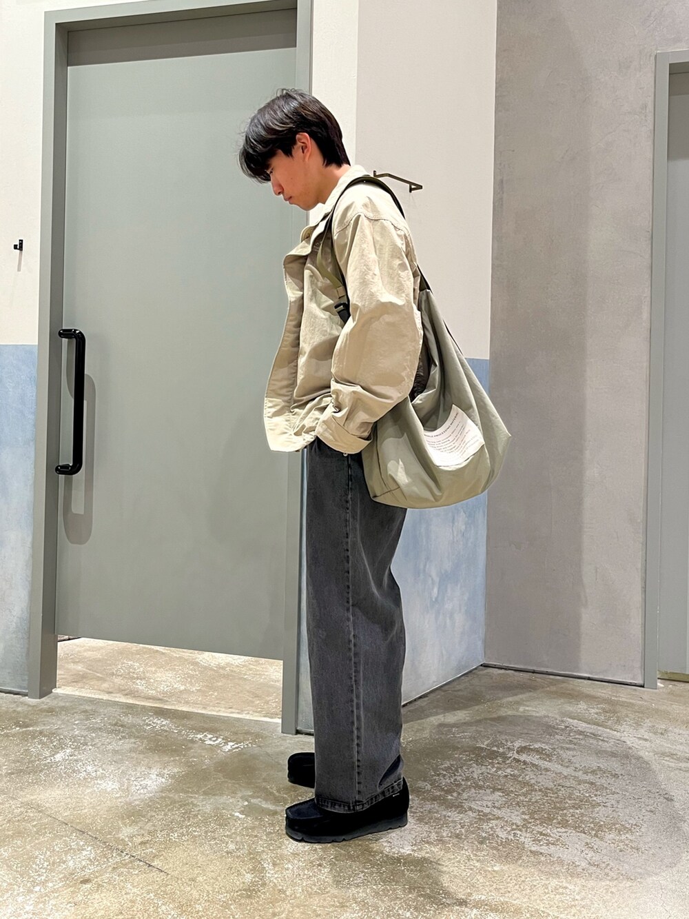 ブラック系のスニーカー、ブラック系のデニムパンツ、グレー系のナイロンジャケットを着用したメンズの春コーディネートの3枚目の写真