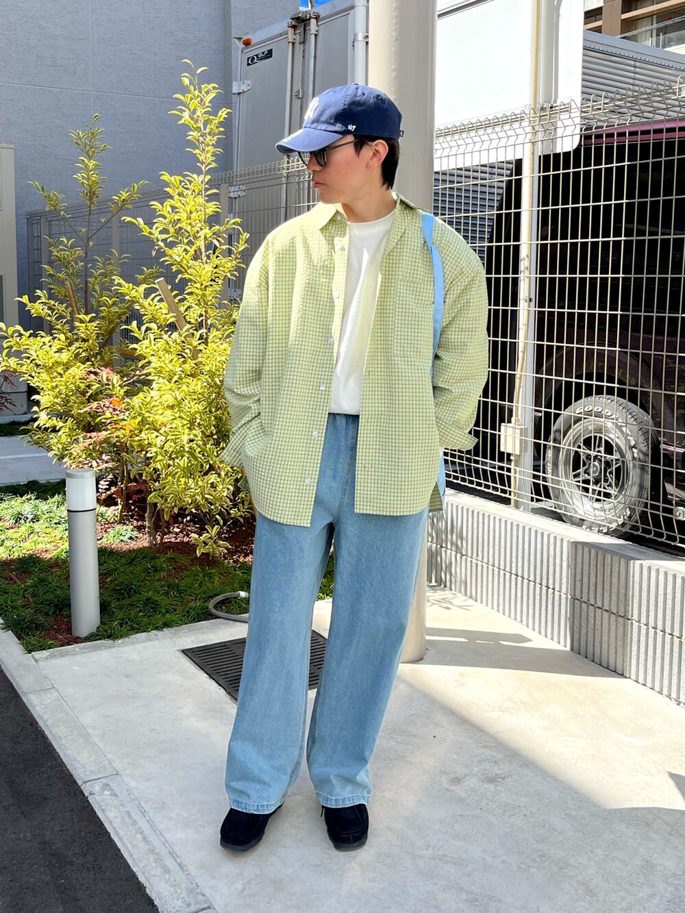 ブラック系のスニーカー、ブルー系のデニムパンツ、ブルー系のトートバッグを着用したメンズの春コーディネートの2枚目の写真