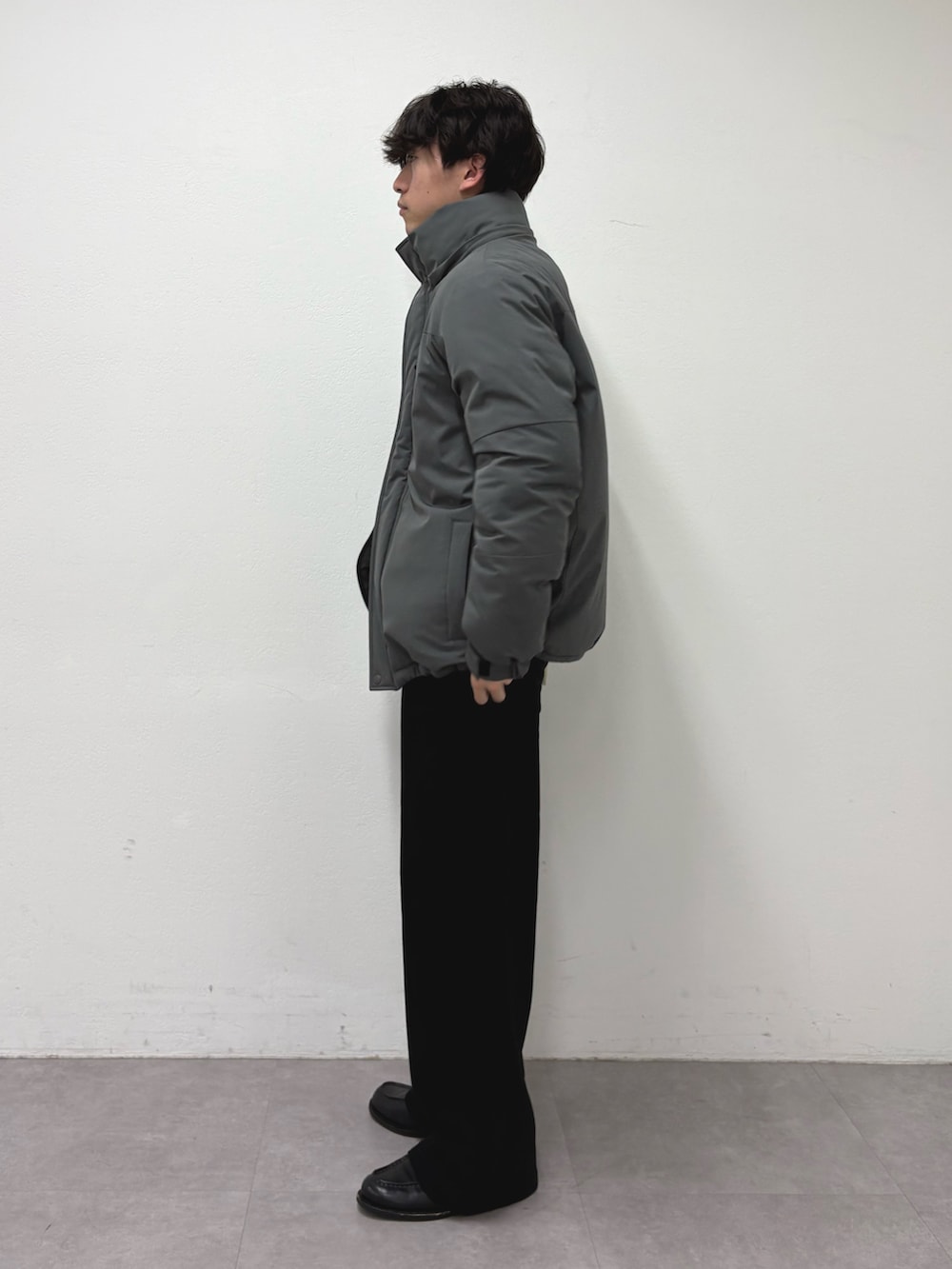 ブラック系のその他パンツ、グレー系のダウンジャケット/コート、グリーン系のニット/セーターを着用したメンズの冬コーディネートの2枚目の写真