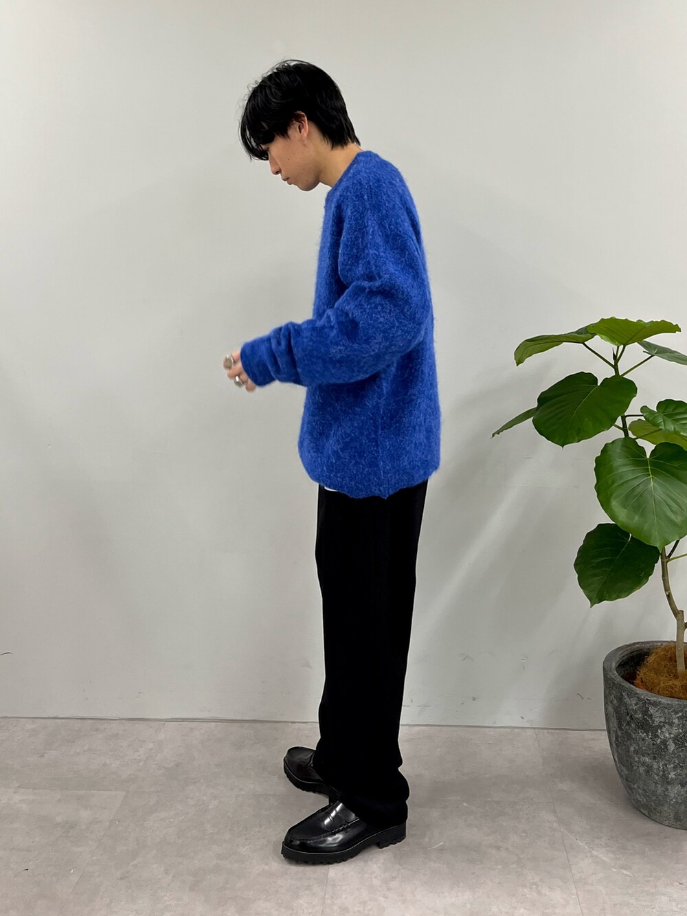 ブルー系のニット/セーター、ブラック系のスラックスを着用したメンズの冬コーディネートの2枚目の写真