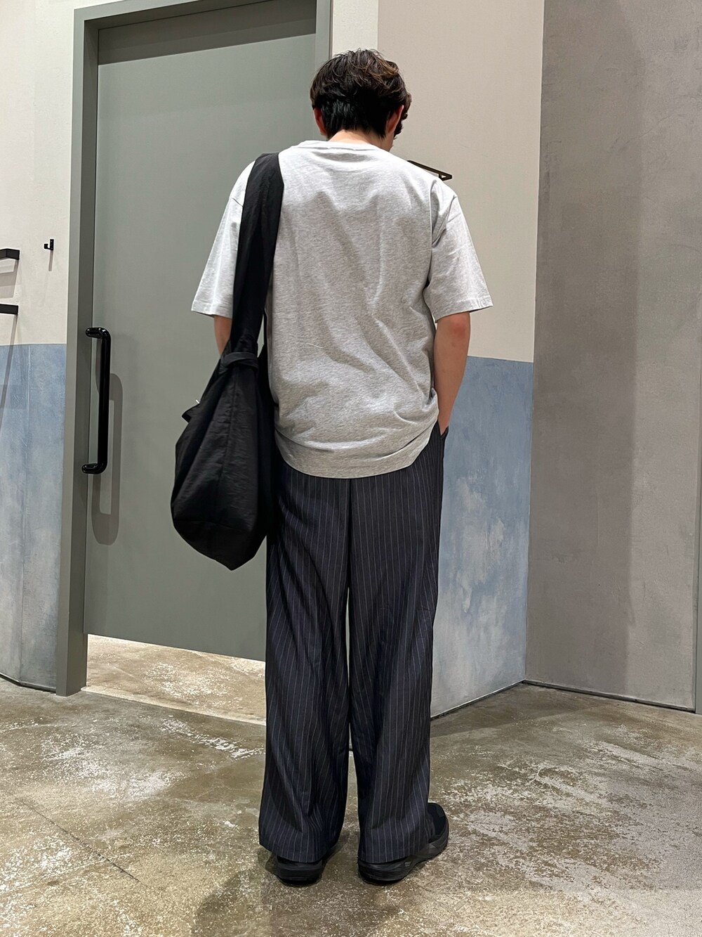 グレー系のTシャツ/カットソー、グレー系のスラックス、ブラック系のショルダーバッグを着用したメンズの夏コーディネートの3枚目の写真