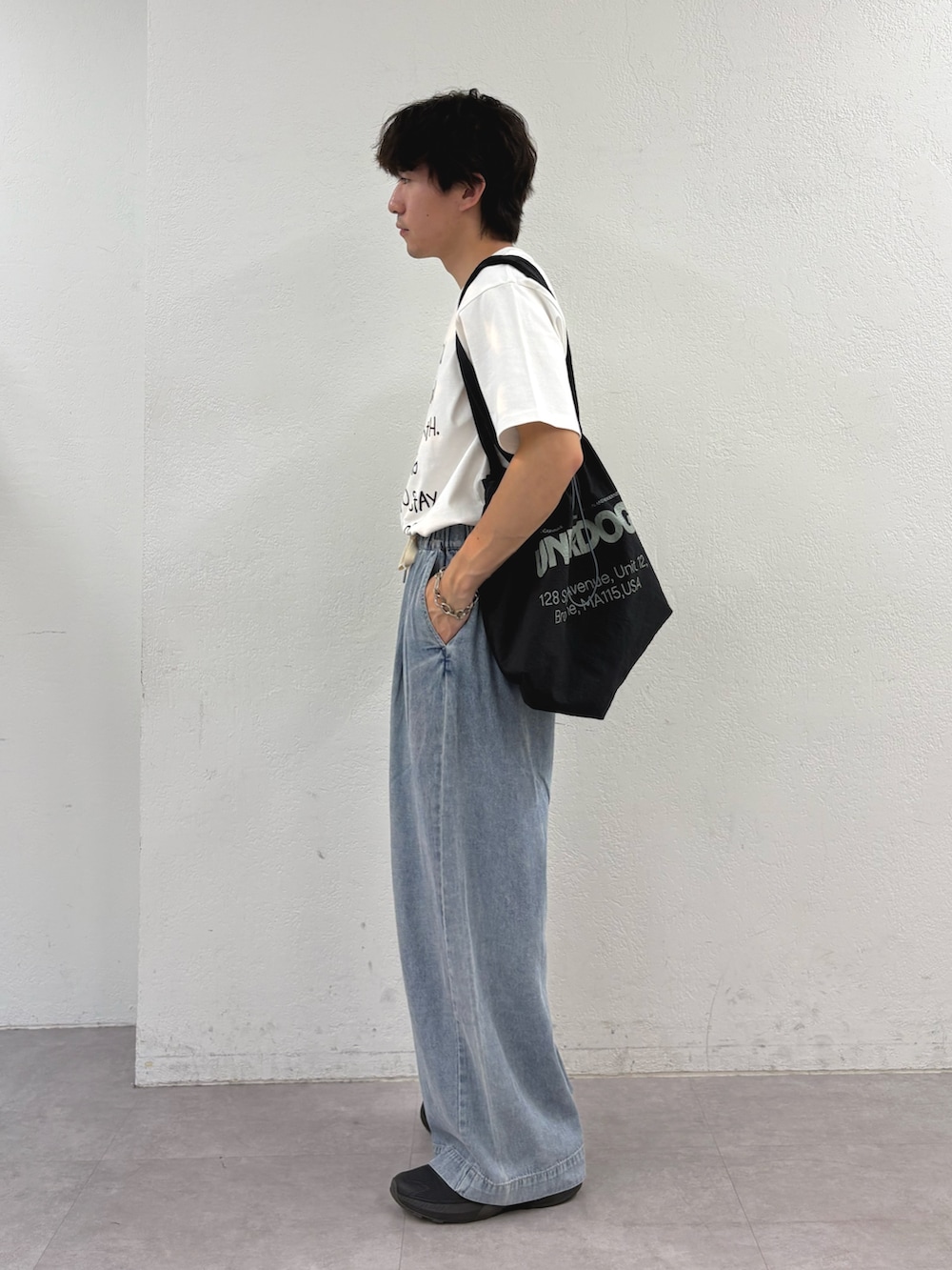 ホワイト系のTシャツ/カットソー、ブラック系のトートバッグ、ブルー系のデニムパンツを着用したメンズの夏コーディネートの2枚目の写真